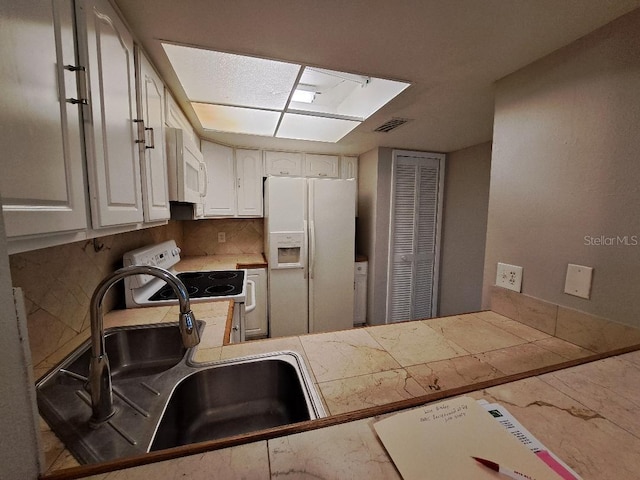 kitchen featuring white appliances, backsplash, white cabinets, sink, and kitchen peninsula