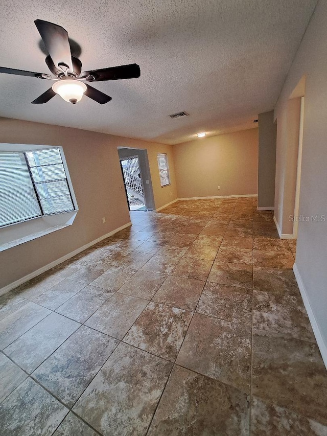 unfurnished room featuring ceiling fan, plenty of natural light, and a textured ceiling