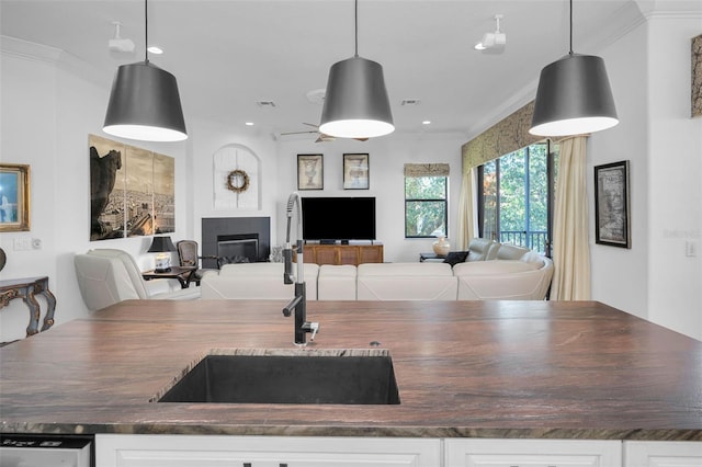 kitchen featuring white cabinets, sink, hanging light fixtures, and a tile fireplace