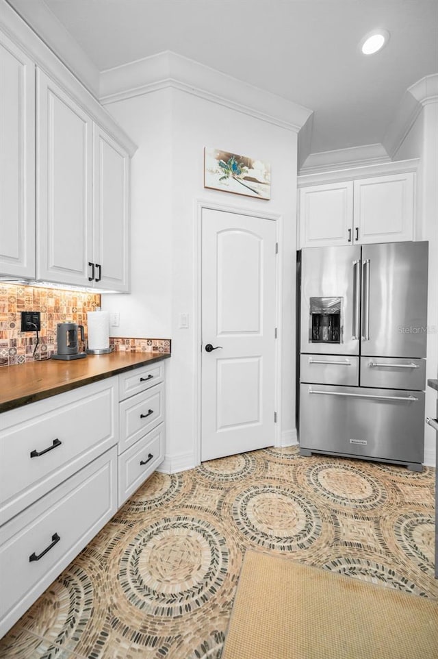 kitchen with white cabinets, backsplash, high end fridge, and ornamental molding