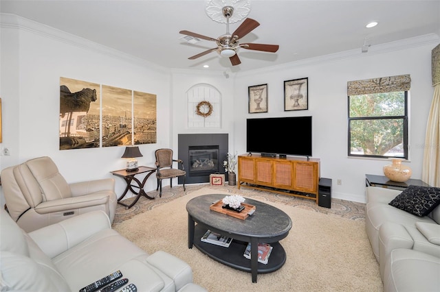 living room featuring ceiling fan, crown molding, and a fireplace