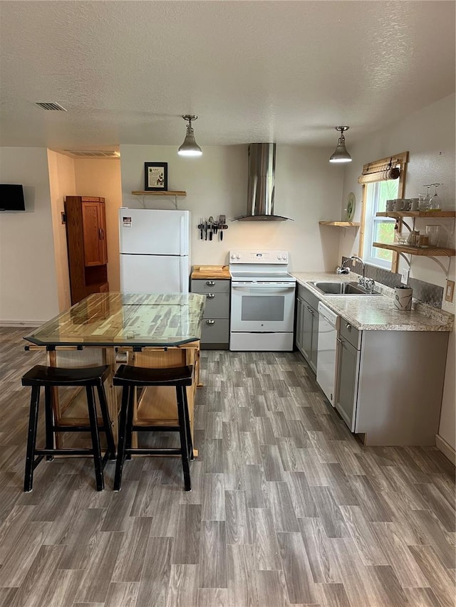 kitchen with white appliances, hardwood / wood-style floors, a textured ceiling, sink, and wall chimney exhaust hood