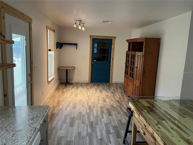 hallway with light hardwood / wood-style floors and a textured ceiling