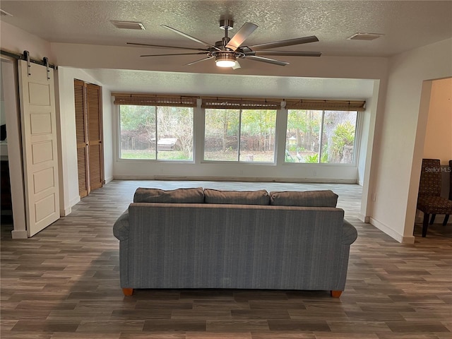 living room with ceiling fan, dark wood-type flooring, and a barn door