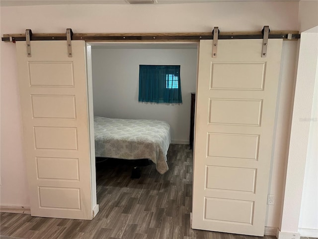 bedroom with dark hardwood / wood-style flooring and a barn door