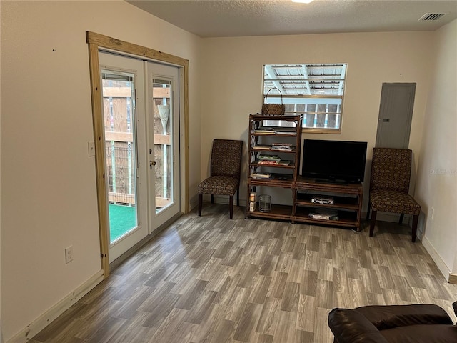 sitting room featuring electric panel, a textured ceiling, and hardwood / wood-style floors