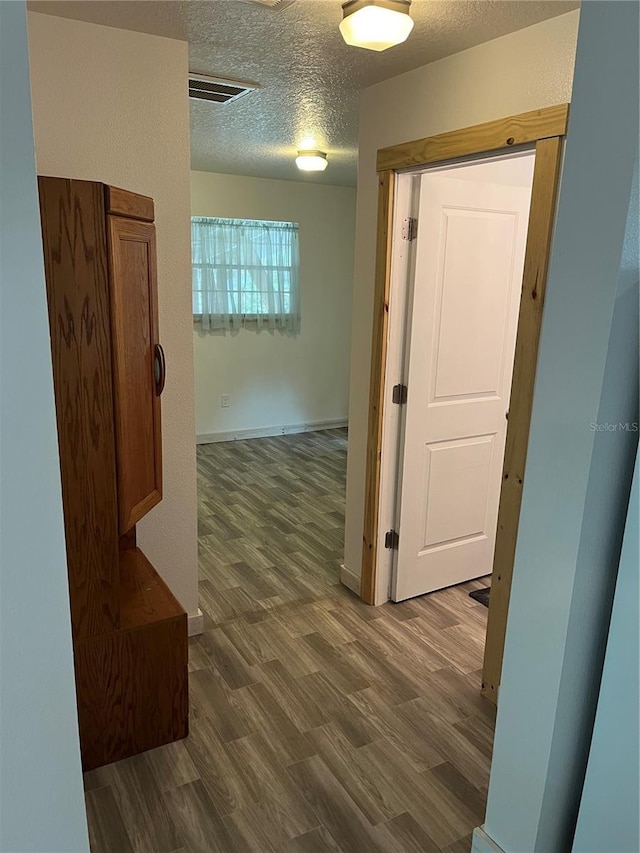 hall featuring a textured ceiling and dark hardwood / wood-style floors