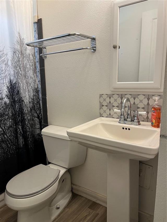 bathroom featuring decorative backsplash, sink, wood-type flooring, and toilet