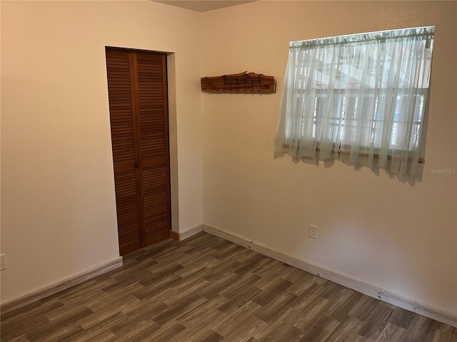 unfurnished bedroom with a closet and dark wood-type flooring