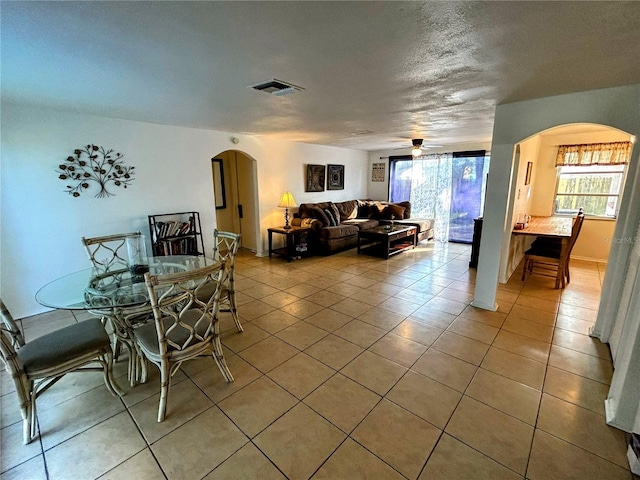 dining area featuring ceiling fan, light tile patterned flooring, and a textured ceiling