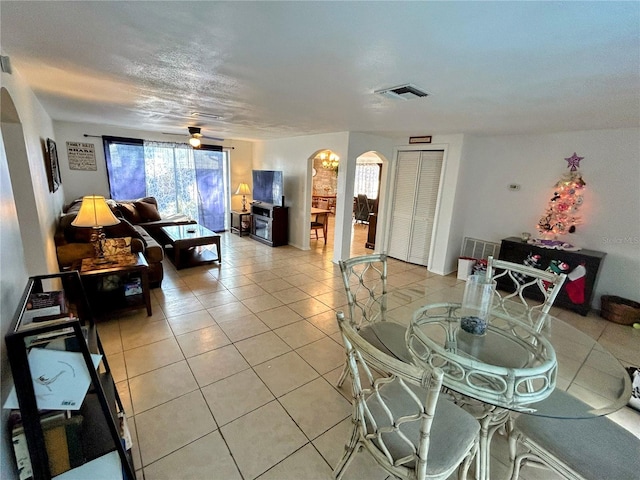 tiled living room featuring ceiling fan and a textured ceiling