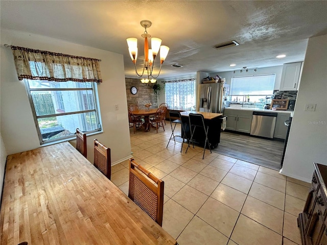 dining room featuring light tile patterned flooring, a chandelier, and a textured ceiling