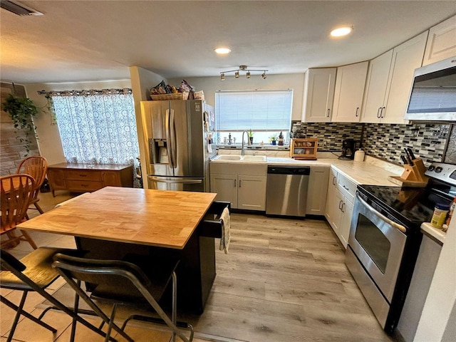 kitchen featuring sink, white cabinets, stainless steel appliances, and light wood-type flooring