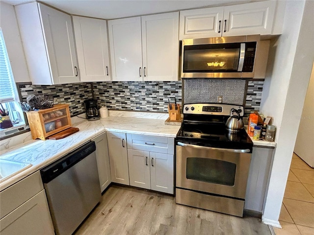 kitchen featuring decorative backsplash, white cabinetry, and stainless steel appliances