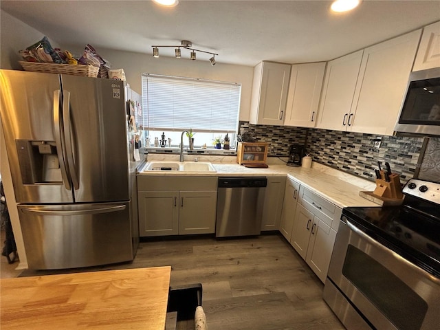 kitchen with white cabinets, appliances with stainless steel finishes, hardwood / wood-style flooring, and sink