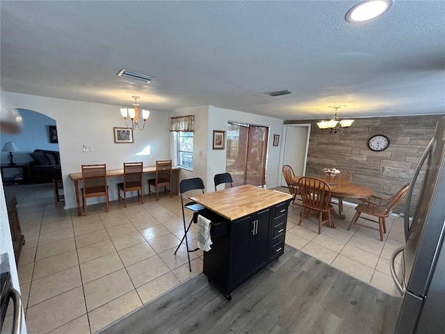 kitchen featuring a chandelier, stainless steel fridge, a center island, and decorative light fixtures