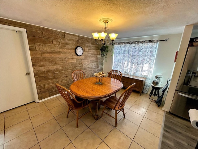 unfurnished dining area featuring light tile patterned floors, a textured ceiling, and an inviting chandelier