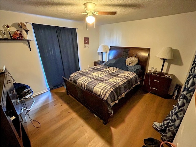 bedroom featuring ceiling fan, hardwood / wood-style floors, and a textured ceiling