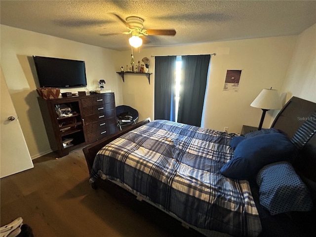 bedroom with ceiling fan, dark carpet, and a textured ceiling