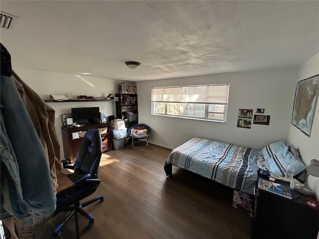 bedroom with a textured ceiling and dark hardwood / wood-style flooring