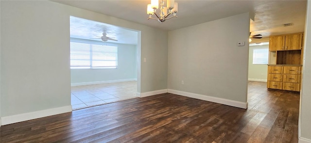 empty room featuring ceiling fan with notable chandelier and hardwood / wood-style flooring