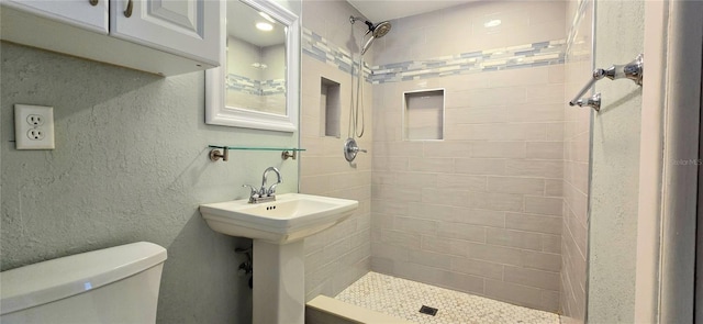 bathroom featuring toilet and tiled shower