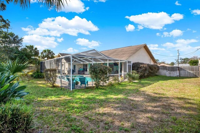 back of house featuring a lanai, a lawn, and a fenced in pool