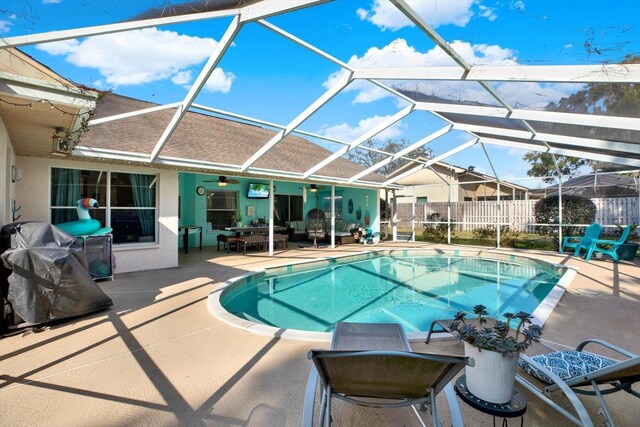 view of swimming pool with ceiling fan, a patio, and glass enclosure