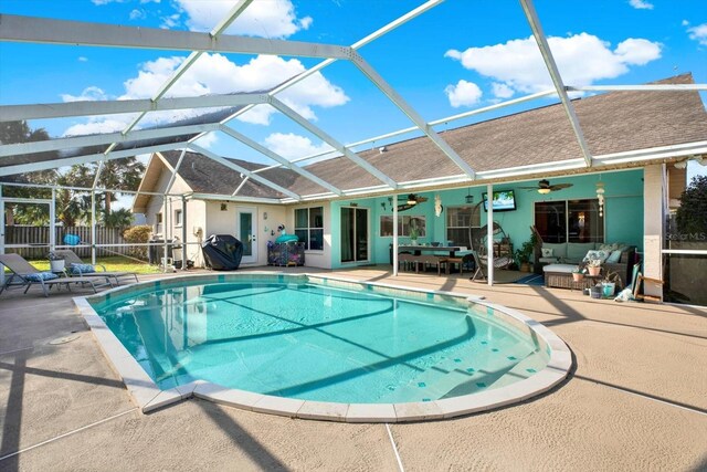 view of swimming pool featuring an outdoor living space, a patio, glass enclosure, and ceiling fan