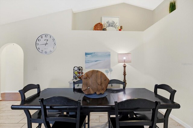 dining space with light tile patterned flooring and vaulted ceiling