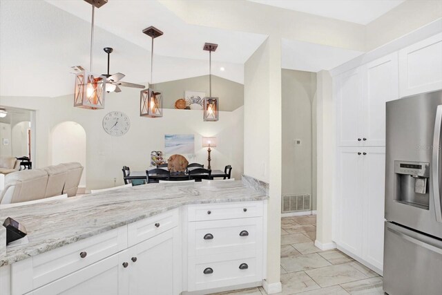 kitchen featuring ceiling fan, stainless steel fridge, pendant lighting, vaulted ceiling, and white cabinets