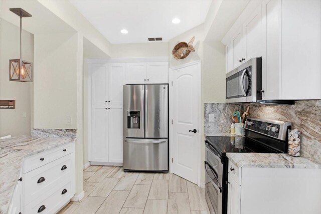 kitchen featuring light stone counters, hanging light fixtures, white cabinets, and stainless steel appliances