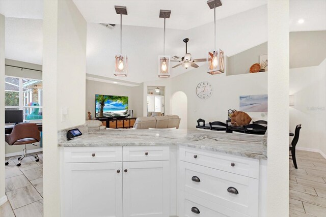 kitchen with white cabinetry, ceiling fan, light stone countertops, and decorative light fixtures