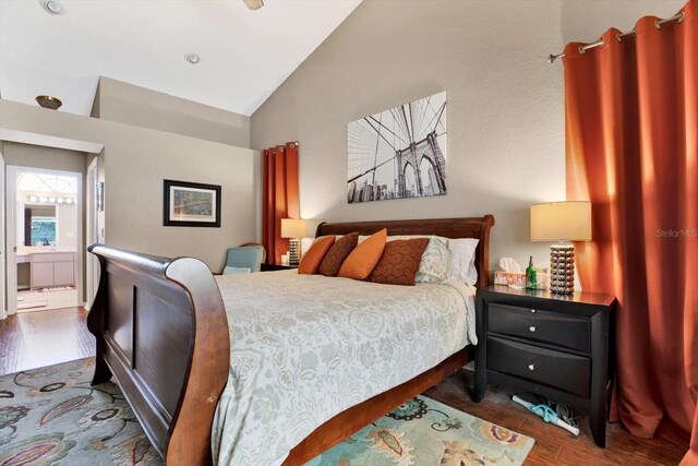 bedroom with connected bathroom, vaulted ceiling, and dark wood-type flooring