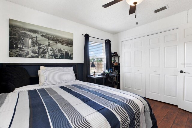 bedroom with a textured ceiling, dark hardwood / wood-style floors, a closet, and ceiling fan