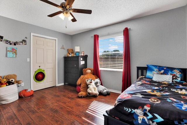 bedroom featuring a textured ceiling, a closet, ceiling fan, and dark wood-type flooring