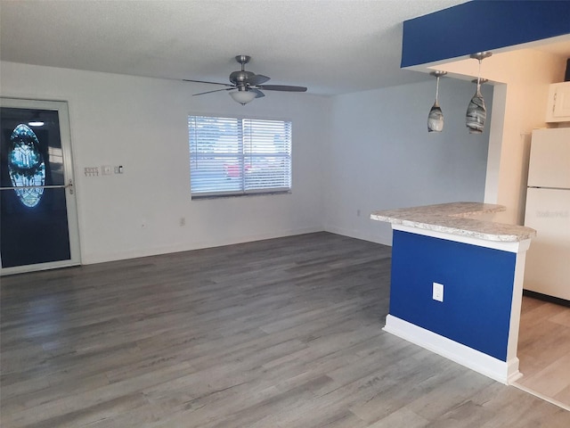 interior space featuring pendant lighting, hardwood / wood-style flooring, ceiling fan, a textured ceiling, and white fridge