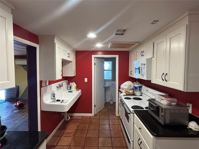 kitchen featuring white cabinetry, sink, white appliances, and dark tile patterned floors