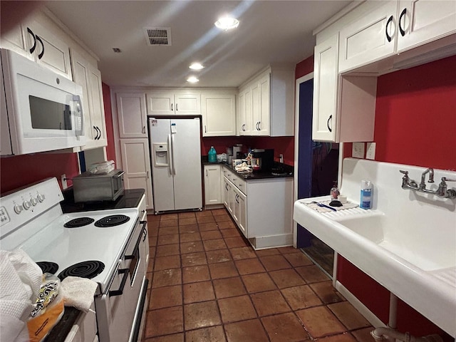 kitchen with white cabinetry, white appliances, and dark tile patterned flooring