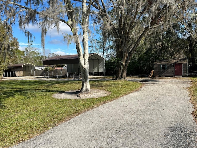 view of front facade with a front lawn, a carport, and a storage unit