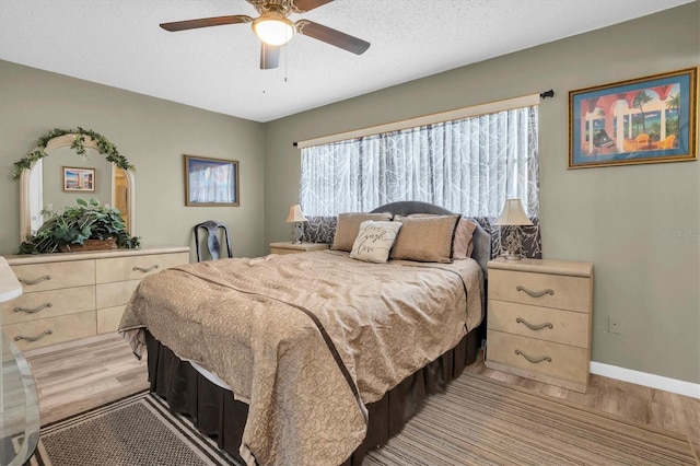 bedroom featuring ceiling fan, light hardwood / wood-style floors, and a textured ceiling