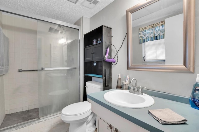 bathroom featuring vanity, a textured ceiling, toilet, and walk in shower