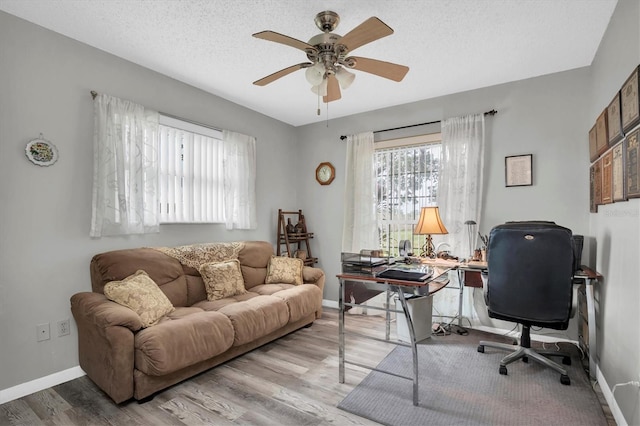 office space with ceiling fan, a textured ceiling, and light wood-type flooring