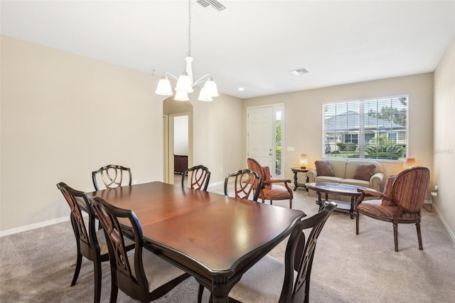 dining space with light carpet and a chandelier