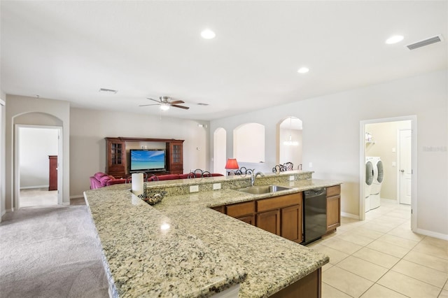 kitchen featuring washer and clothes dryer, dishwasher, a center island with sink, and sink