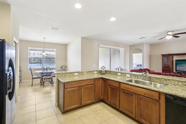 kitchen with light stone countertops, sink, black dishwasher, stainless steel refrigerator with ice dispenser, and decorative light fixtures