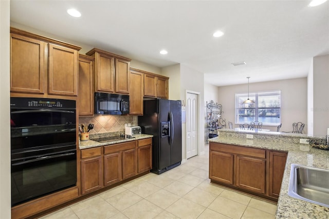 kitchen with light stone countertops, sink, tasteful backsplash, pendant lighting, and black appliances