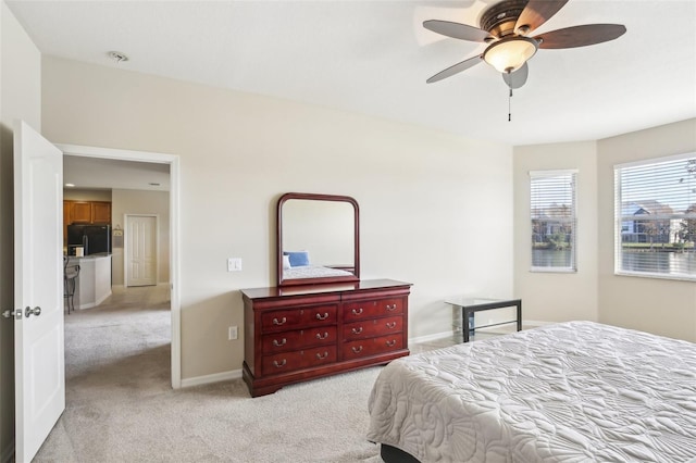 bedroom featuring ceiling fan, black fridge, and light colored carpet