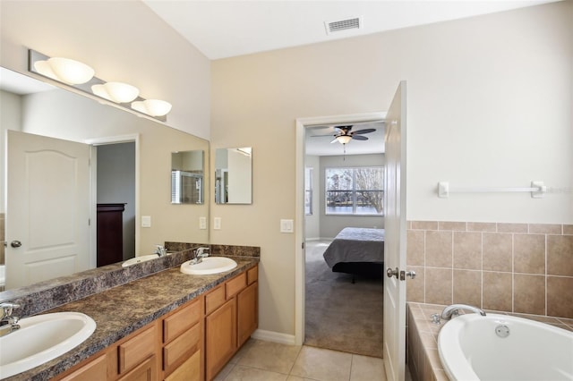 bathroom with tiled tub, ceiling fan, tile patterned flooring, and vanity