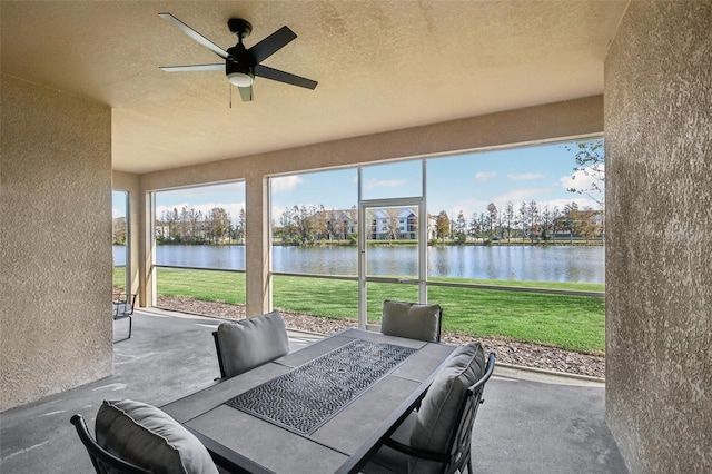 sunroom with a water view and ceiling fan